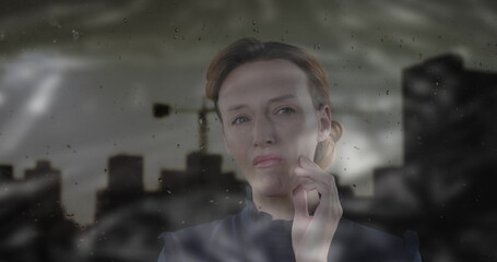 Image of cityscape over sad caucasian woman touching her cheek