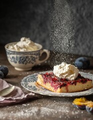 Delicious homemade plum cake with a spelt flour base topped with cream on a wooden table