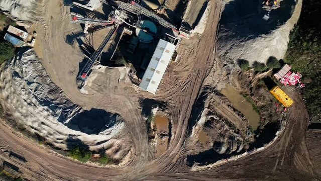 Bird's eye view over a quarry plantation and cranes and tractors digging the ground on a sunny day
