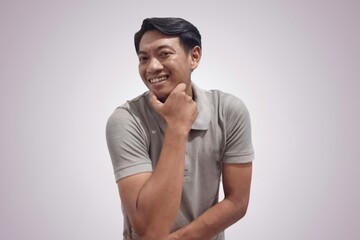 Young asian positive man in gray casual shirt standing with happy smile,with copyspace area