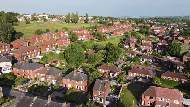 Aerial of a small village with beautiful houses in the UK on a sunny day surrounded by green fields