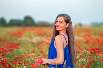 Naklejka na ściany i meble portrait of elegant young woman in poppy field in evening sunlight