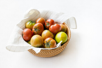 Fresh daejeo tomato in a rattan basket under warm sunlight indoor natural light on white background 