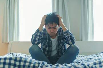 Foto op Canvas Unhappy Japanese man with headache sitting on bed © AI_images