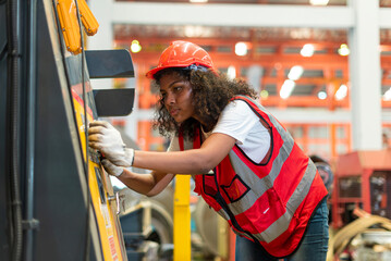African female worker working with remote control's operating crane or lifting beam in factory