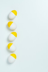 Yellow painted easter eggs aligned in a row on white background