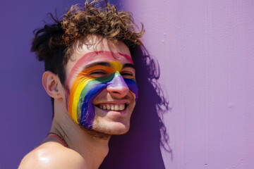 Happy smiling man, face painted with rainbow LGBT pride flag in LGBTQ celebration parade fun party, copy space for text