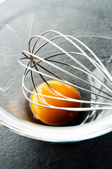 Egg yolk with a whisk in glass bowl