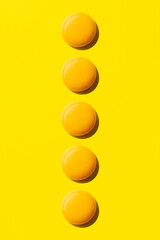 Egg yolks aligned in a row on yellow background