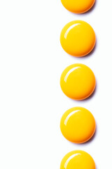 Egg yolks aligned in a row on white background
