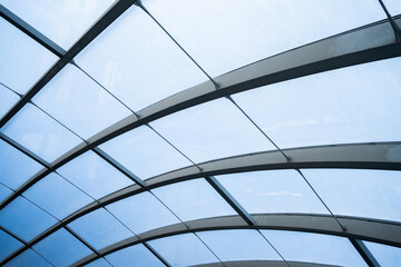 A large, curved glass structure with a blue tint. The glass is arranged in a way that creates a...