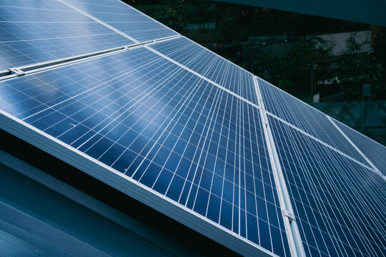 A solar panel is shown in the image, with a blue and silver color scheme. The panel is installed on a roof, and it is a large, multi-panel system