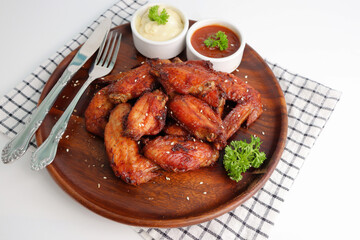 Cooked grilled chicken wings marinated with seasonings Placed on an old wooden tray on a white background
