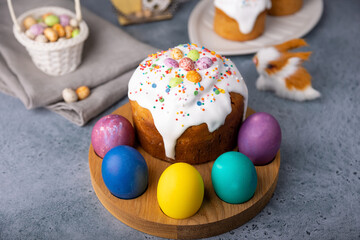 Easter kulich with candied fruits in white glaze with colorful sprinkles and painted eggs....