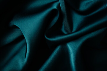 Emerald green silk or satin, draped fabric, elegant background.