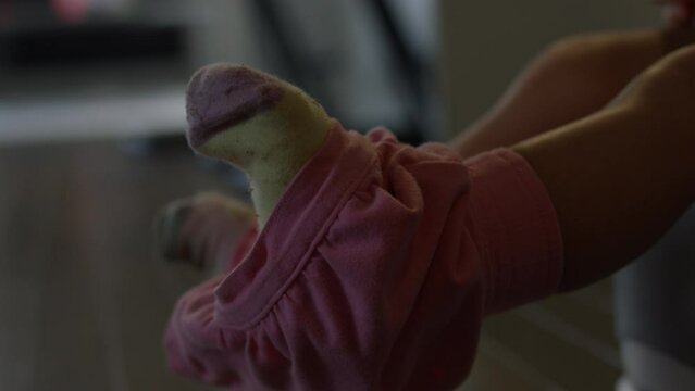 Toddler girl learning to use potty - close up on feet playing in the air