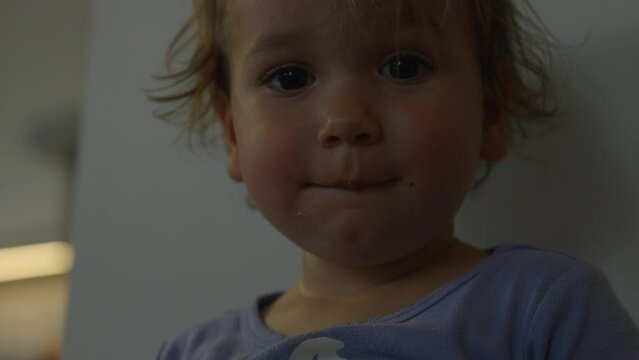 Toddler girl using potty looks towards camera and around - close up on face