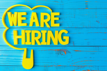 Vibrant "We Are Hiring" Sign on Blue Wooden Background
