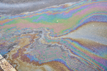 Fuel stain on wet asphalt. Colored stains from a gasoline leak on the road
