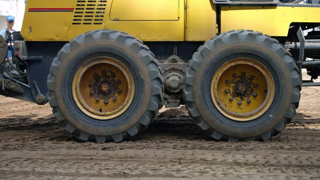 A closeup shot of the yellow bulldozers tires as it rolls along a dirt road, showcasing the tread pattern and heavyduty construction of the rubber wheels