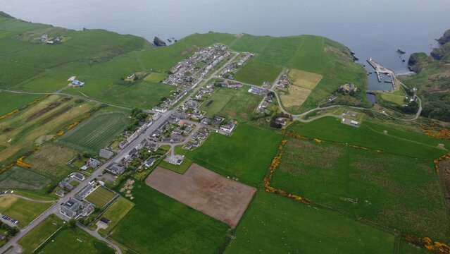 Aerial view of rural houses on the green coastline in Lybster, Scotland