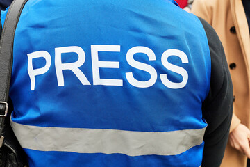 journalist in a blue vest with the inscription press at a rally