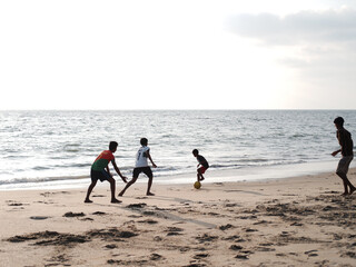 Fototapeta na wymiar Boys playing football (soccer) on the beach
