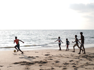 Fototapeta na wymiar children playing soccer ( football) on the beach