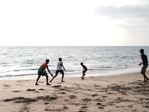 Boys playing football (soccer) on the beach