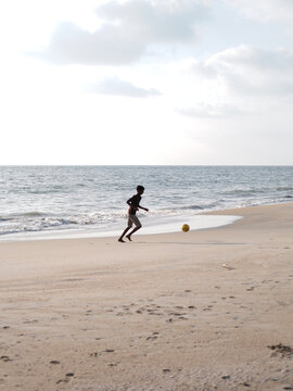 child playing with football on the beach