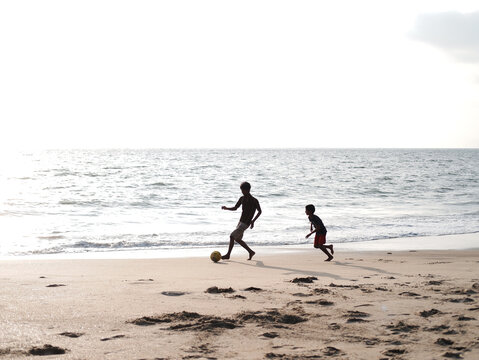 Boys playing football on the beach
