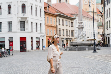 Happy woman wearing stylish outfit exploring of european old town. Travel Vacation Europe.