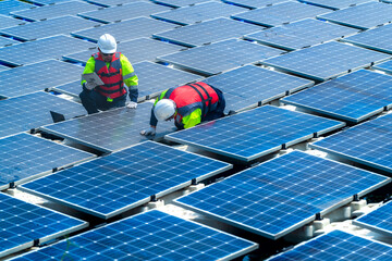 Engineers in safety gear inspect solar panels at a renewable energy farm, ensuring sustainable...