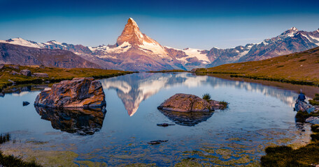 Deep sky above the Matterhorn peak. Calm summer dawn on Stellisee lake. Spectacular morning scene...
