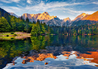 Mangart peak reflected in the calm waters of Fusine lake. Stunning summer view of Julian Alps,...