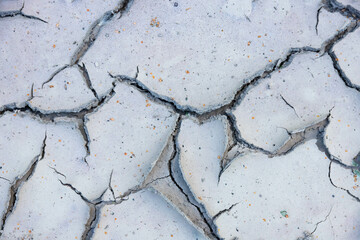 Large cracks in the ground near dry bodies of water in the dry season.
