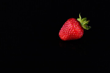 Red strawberries on a black background. Sweet life concept.