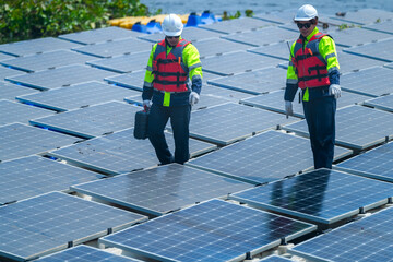 Two technicians in reflective vests are conducting maintenance on a vast array of photovoltaic...