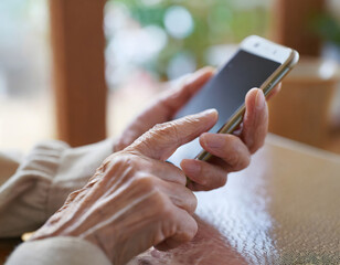 女性シニアがリビングでスマートを操作している手元