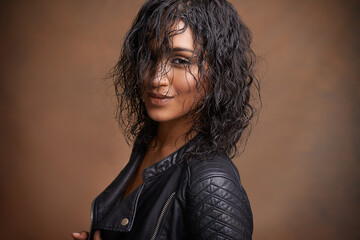 Fashion, portrait and leather jacket with woman, aesthetic and stylish clothes on brown studio...