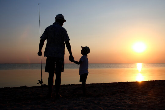 A Happy father and child fishermen catch fish by the sea on nature silhouette travel