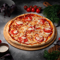 Tomato and cheese pizza with spiced tomatoes and cheese on a grey table