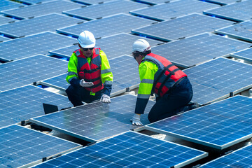Engineers in safety gear inspect solar panels at a renewable energy farm, ensuring sustainable...