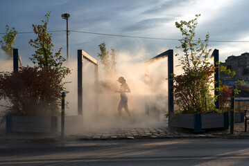 Jogging woman in water vapor cloud on a street