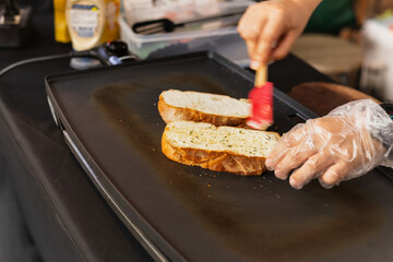 Woman cooking garlic bread with and herbs on iron pan.