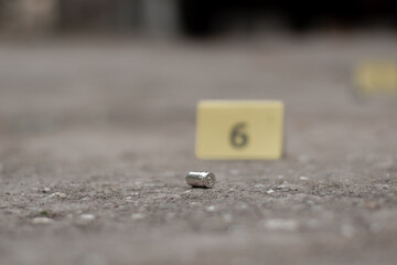 Pistol bullet shell on cement floor with blurred number six yellow paper background, concept for investigation and crime by using gun, soft focus.