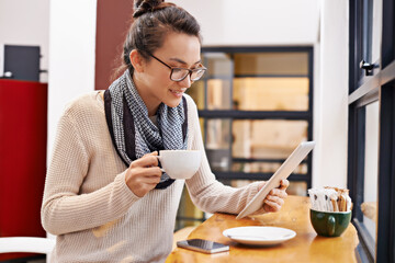 Woman, coffee shop and tablet with freelancer job and social media in cafe with cappuccino....