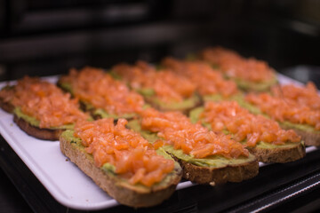 a tray of food with salmon on it and avocado on the bottom