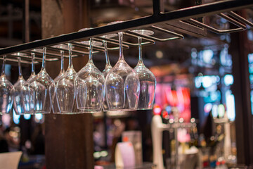 a row of wine glasses hanging from a bar.