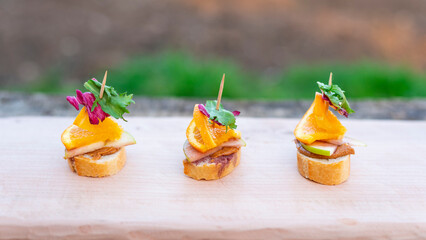Finger food, canapes with cheese, salad, orange and bacon.